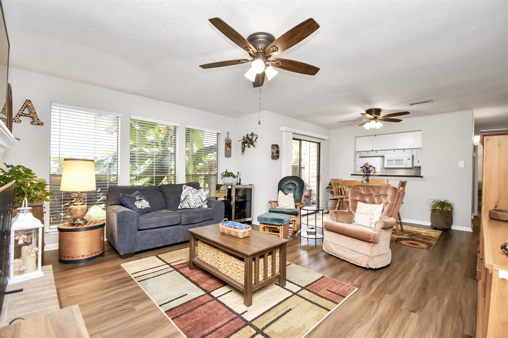 Welcome to this is a cozy, well-lit living room with modern flooring, and a pleasant neutral color scheme. The open floor plan provides a seamless transition to the adjacent kitchen area.