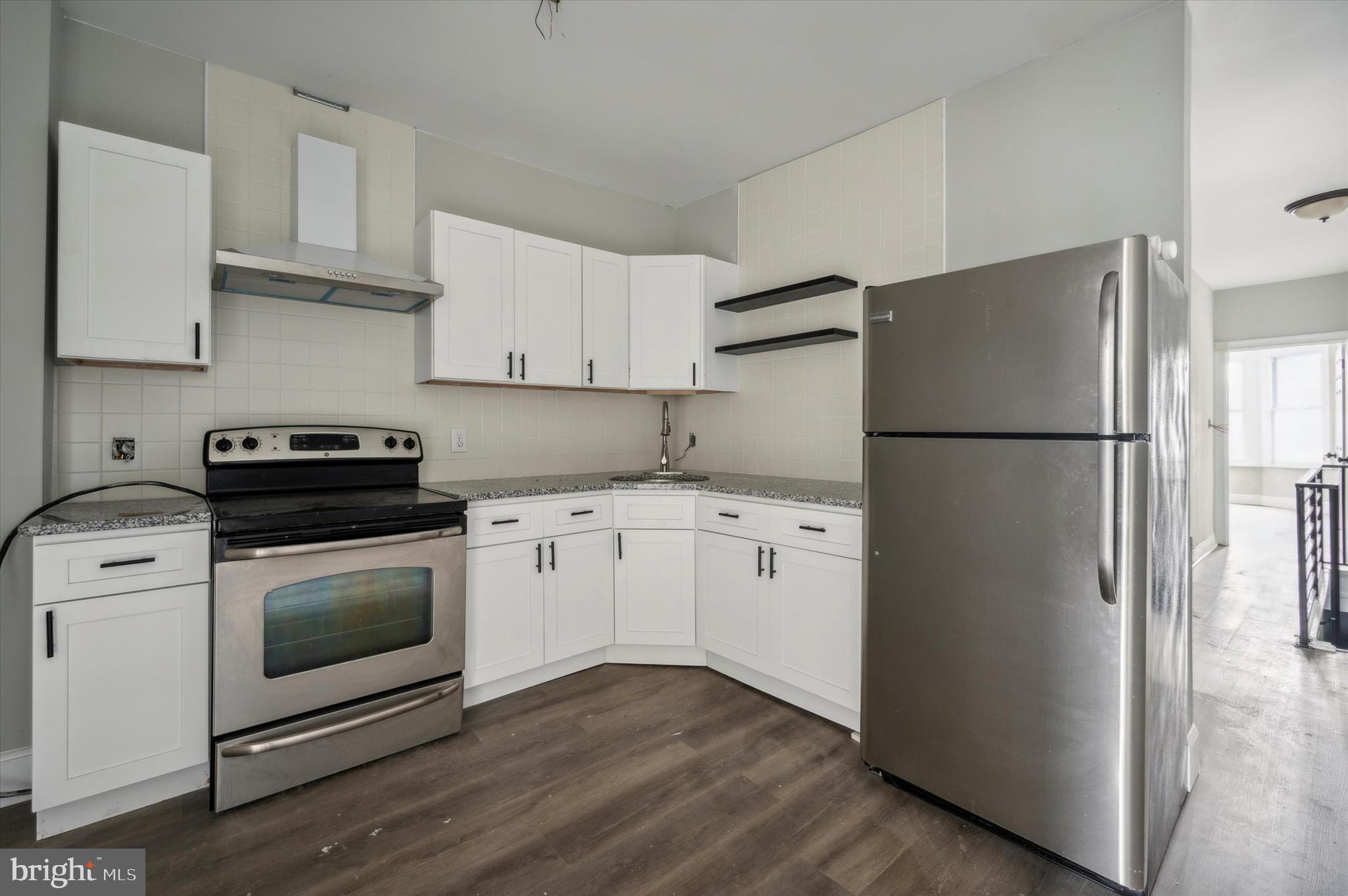 a kitchen with cabinets stainless steel appliances and wooden floor