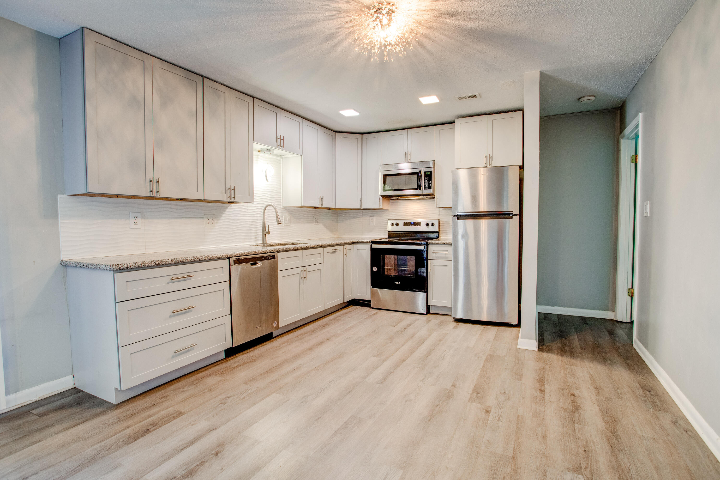 a kitchen with stainless steel appliances granite countertop a refrigerator sink and white cabinets