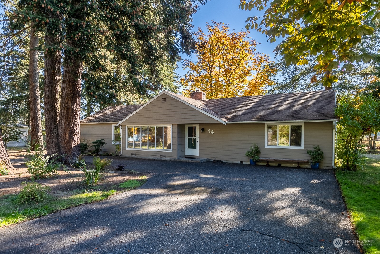 a front view of a house with a garden and trees