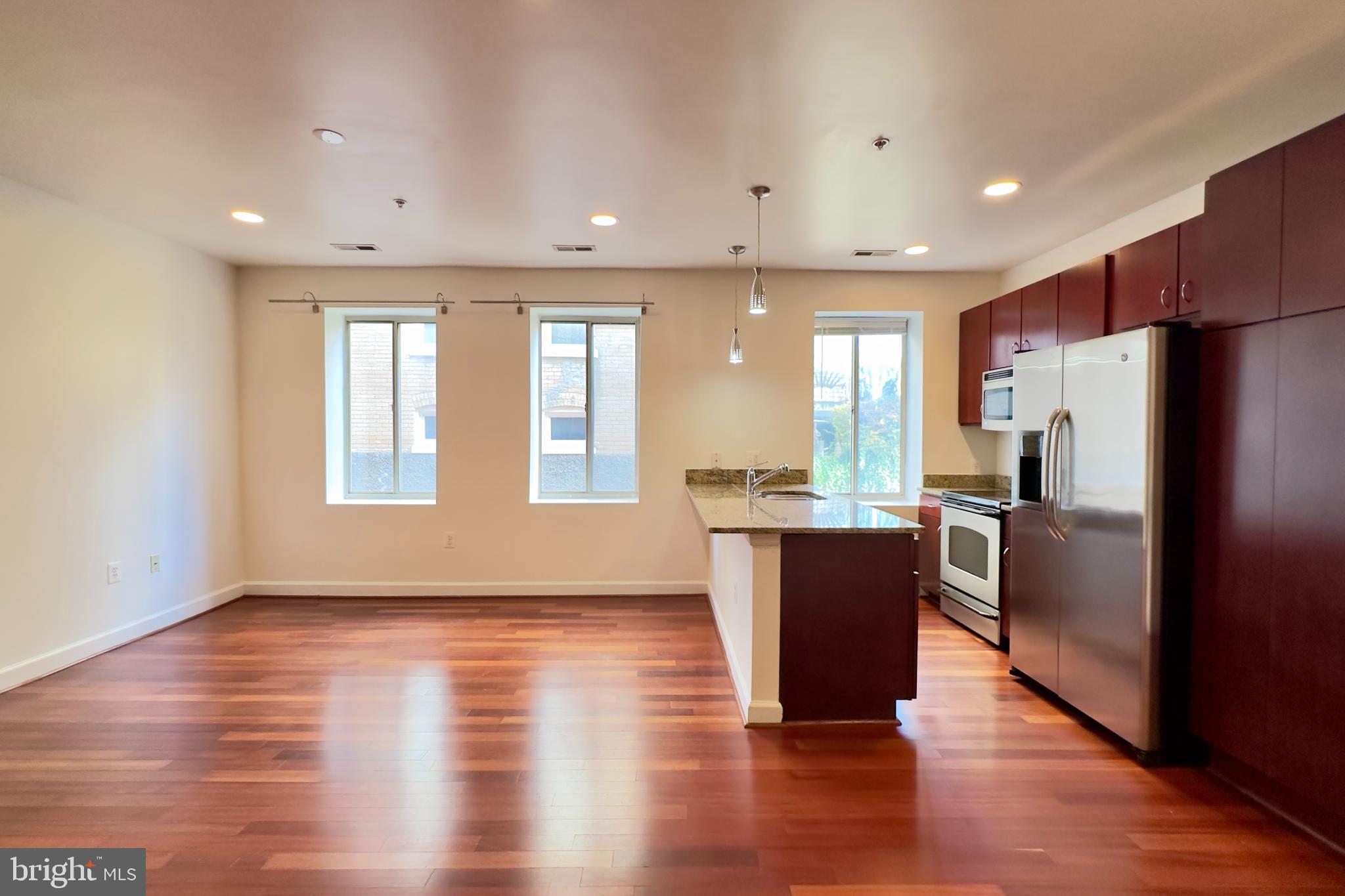 a kitchen with a refrigerator and wooden floor