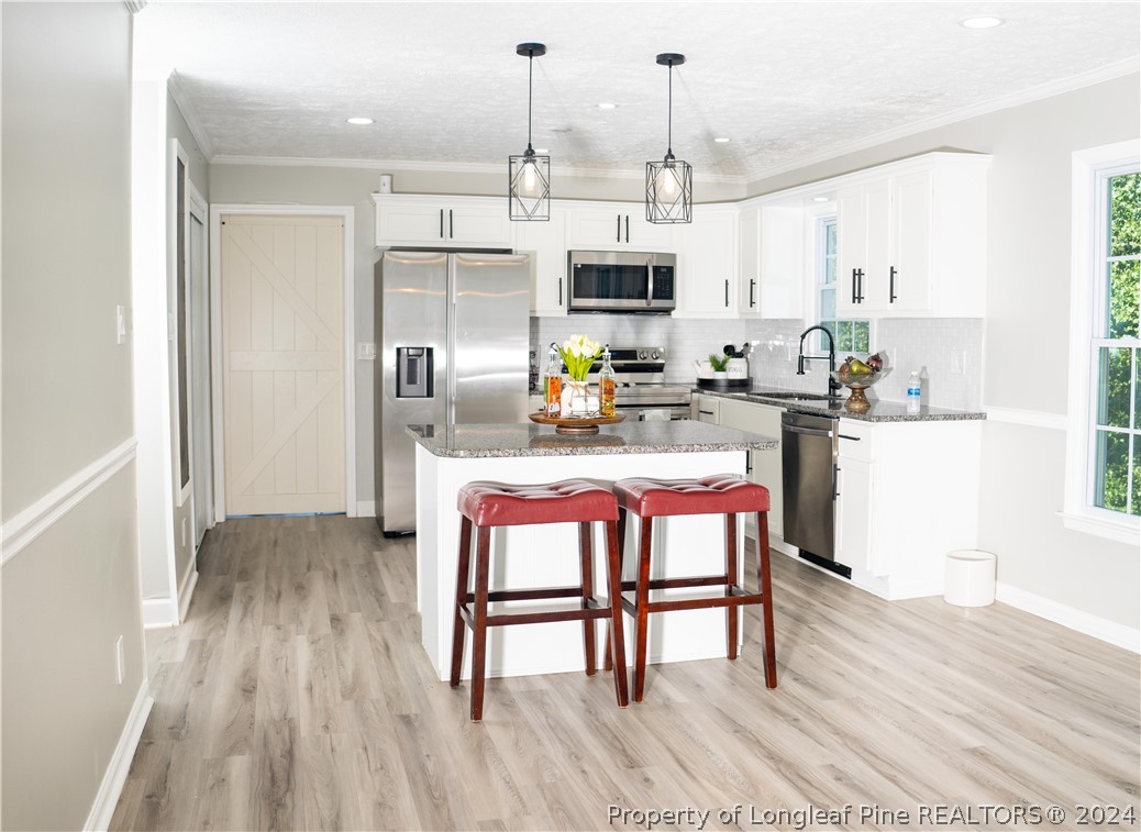 a kitchen with stainless steel appliances a dining table chairs stove refrigerator and cabinets