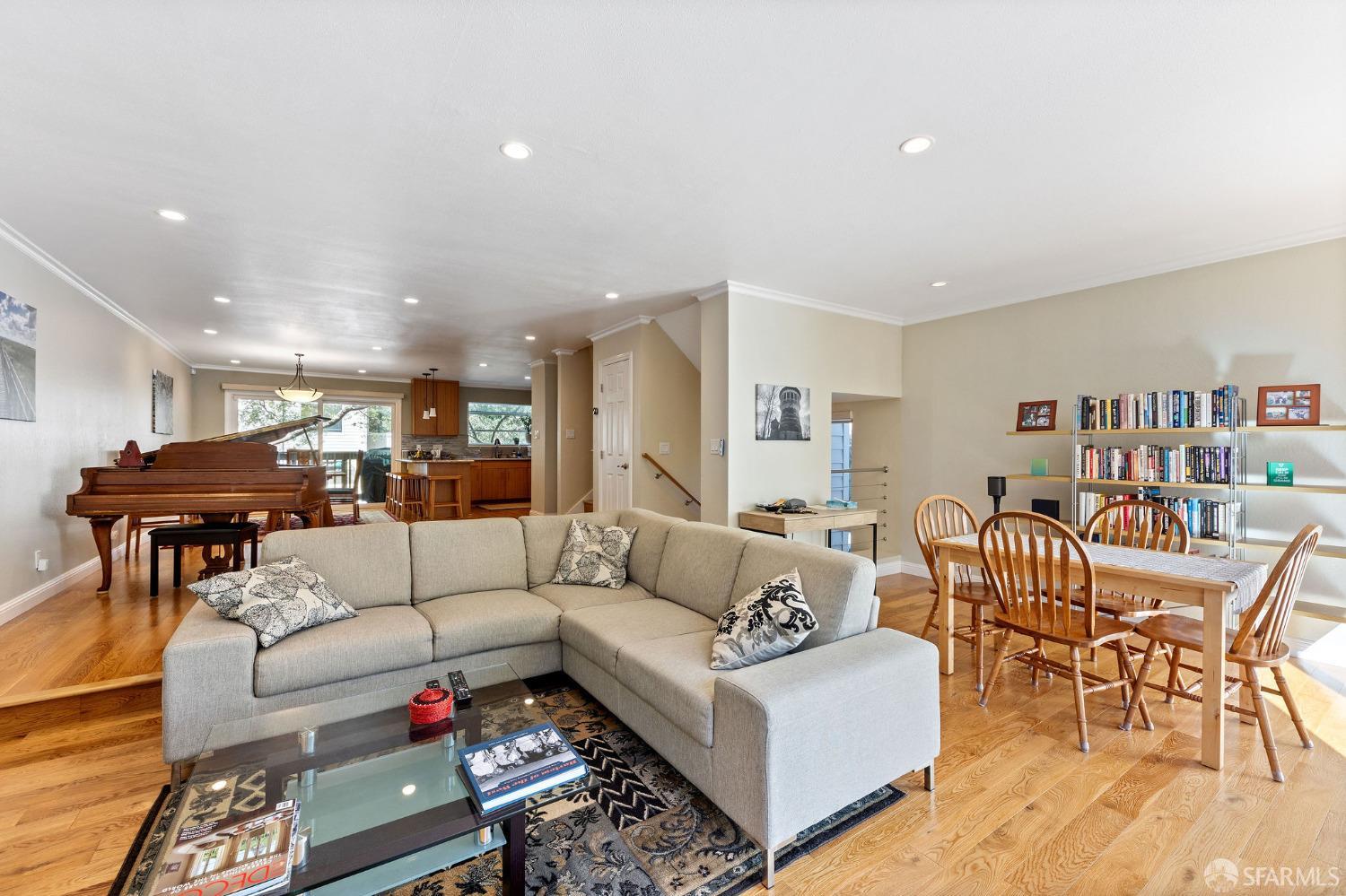 a living room with furniture and a dining table with wooden floor