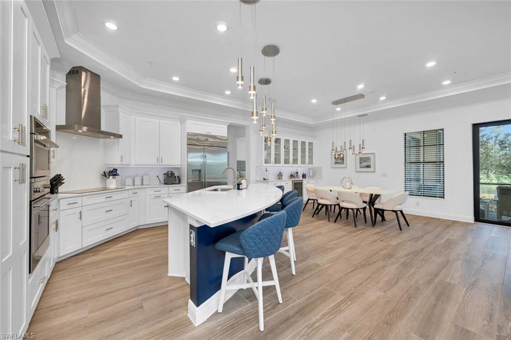 a kitchen with stainless steel appliances kitchen island granite countertop a table chairs sink and cabinets