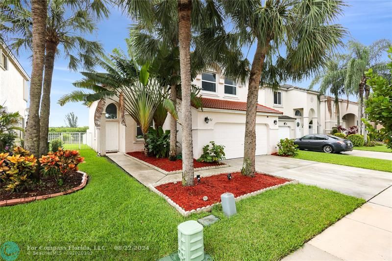 a view of a house with a yard and palm trees