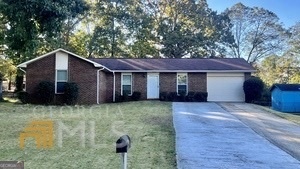 a front view of house with yard and trees in the background