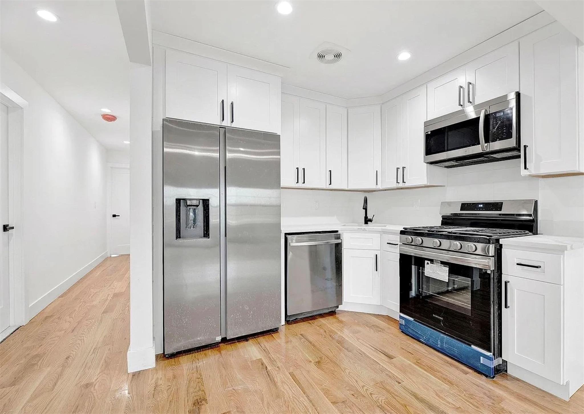 Kitchen featuring white cabinetry, stainless steel appliances, and light hardwood / wood-style floors