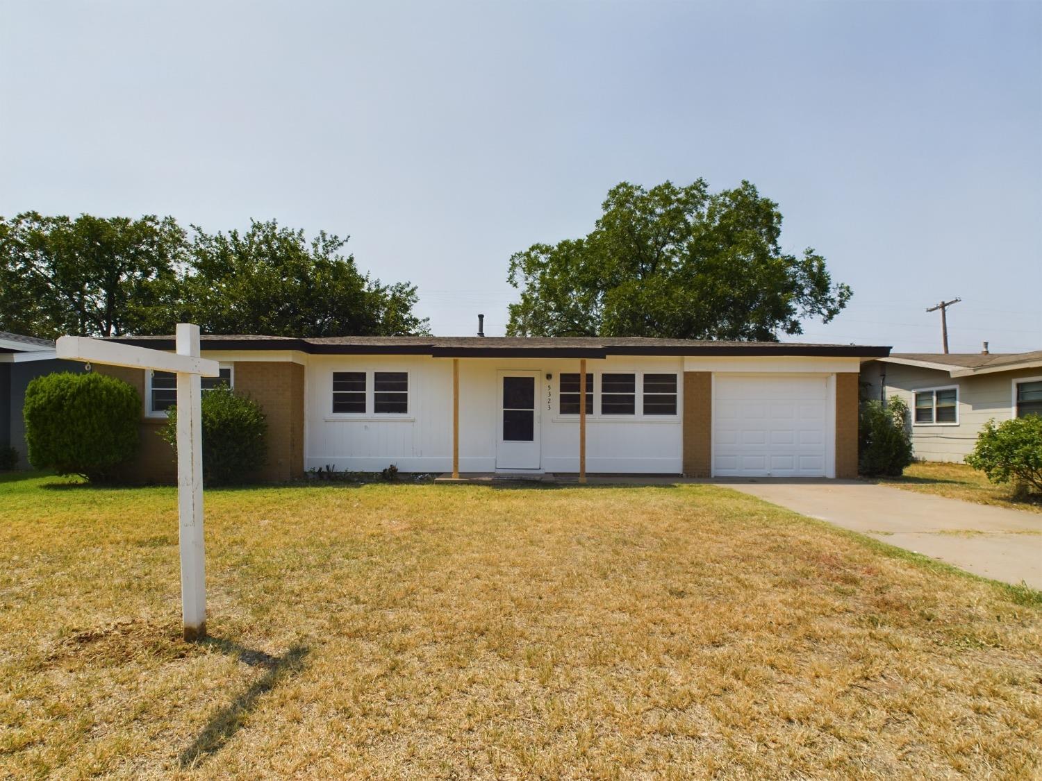 a front view of house with yard and trees in the background