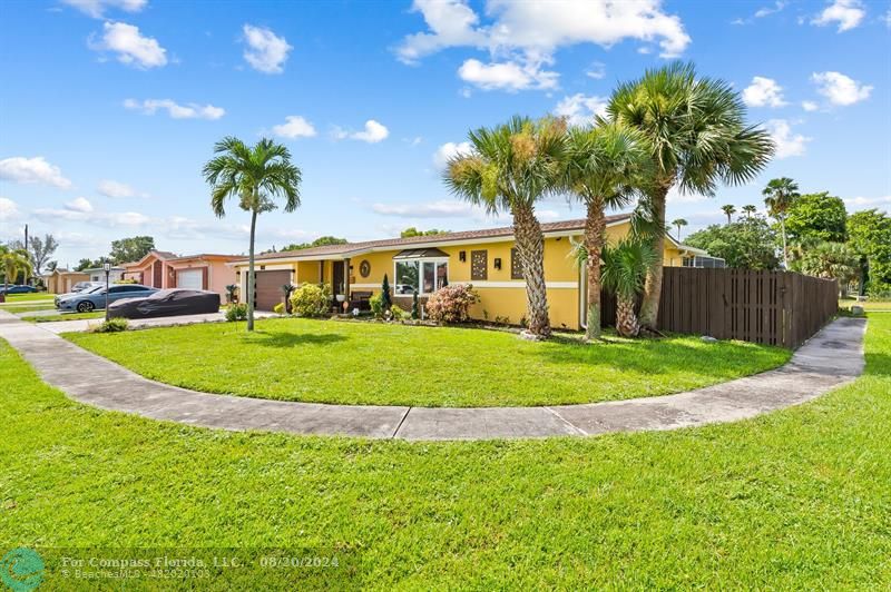 a view of a house with a big yard and palm trees