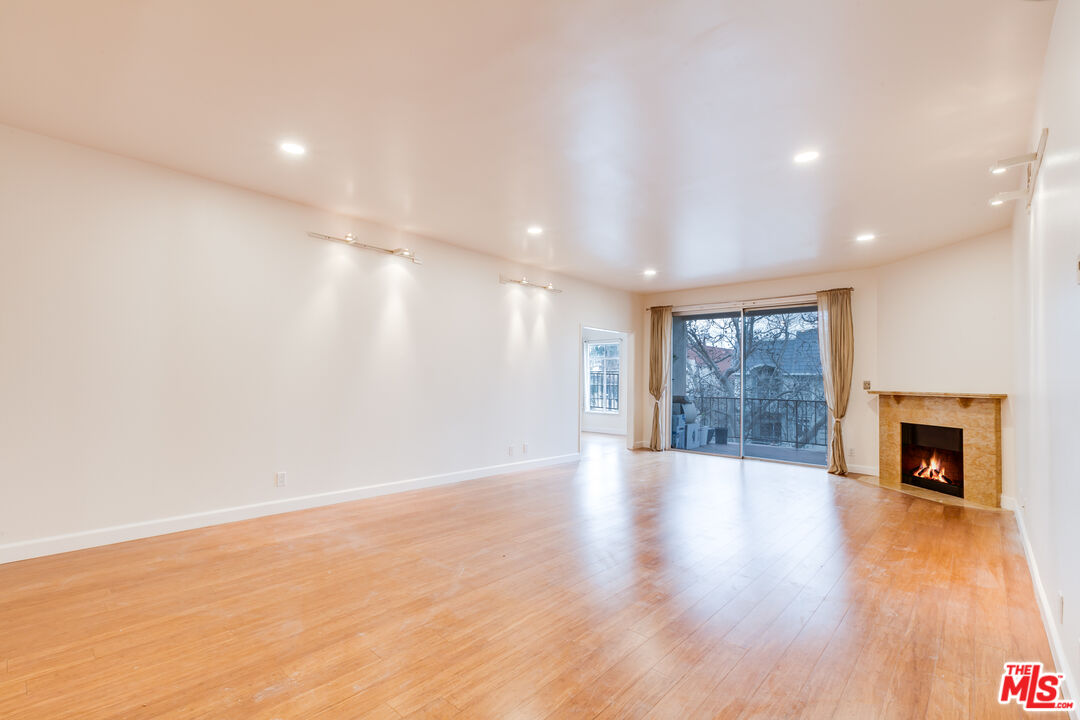 a view of an empty room with wooden floor and a fireplace