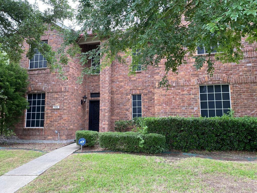 a view of a brick house with a yard and large tree