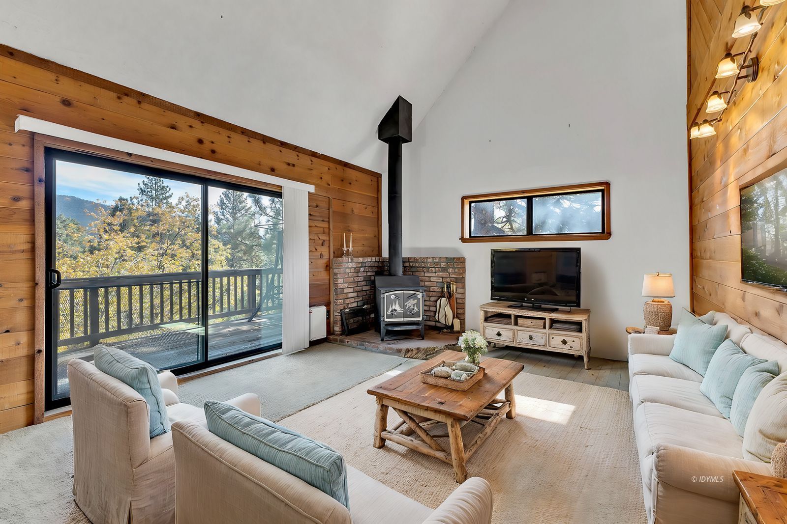 a living room with furniture a flat screen tv and a floor to ceiling window