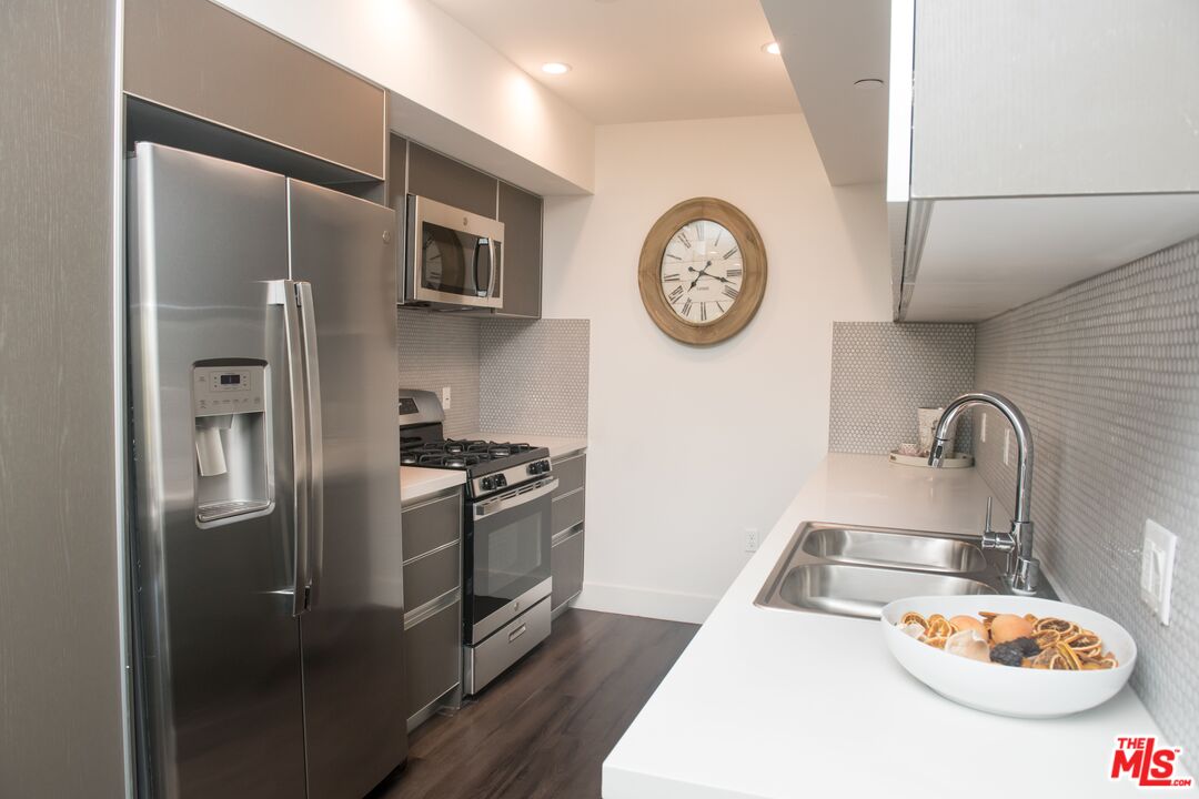 a kitchen with stainless steel appliances granite countertop a sink and a refrigerator