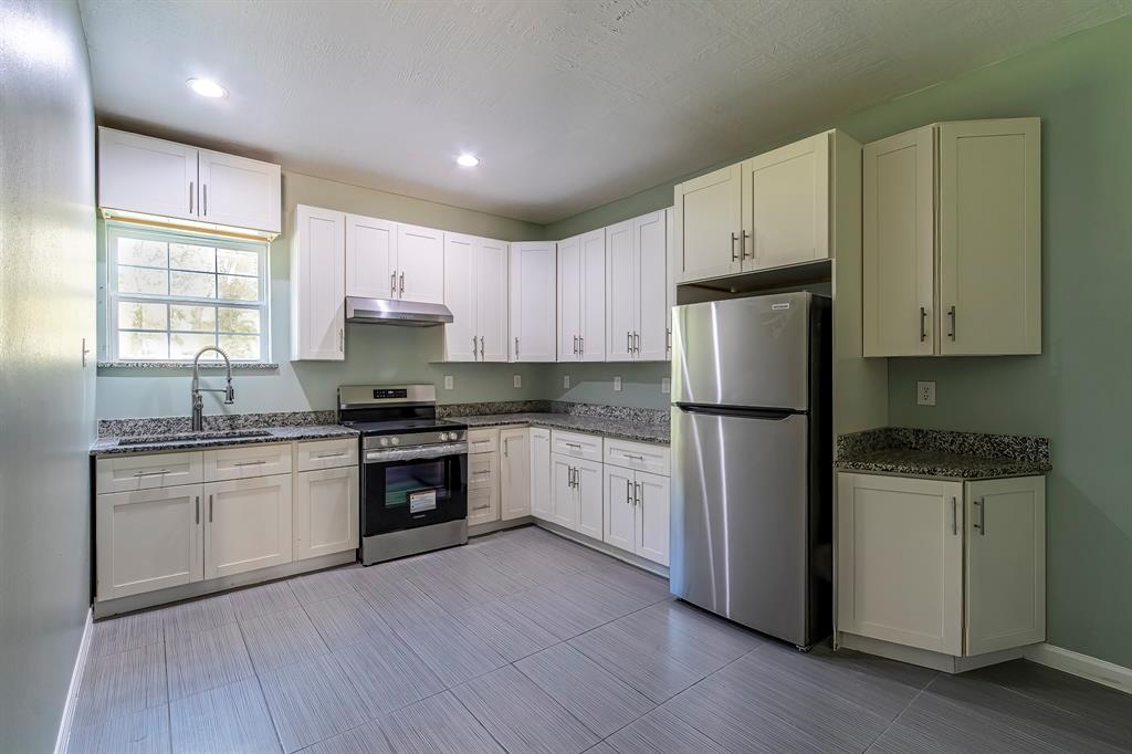 a kitchen with granite countertop white cabinets and white appliances