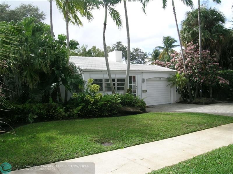 a view of a white house with a yard and palm trees