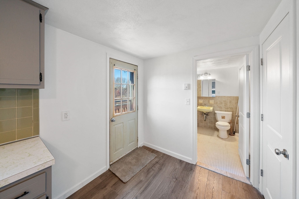 a view of a hallway with wooden floor and a bathroom