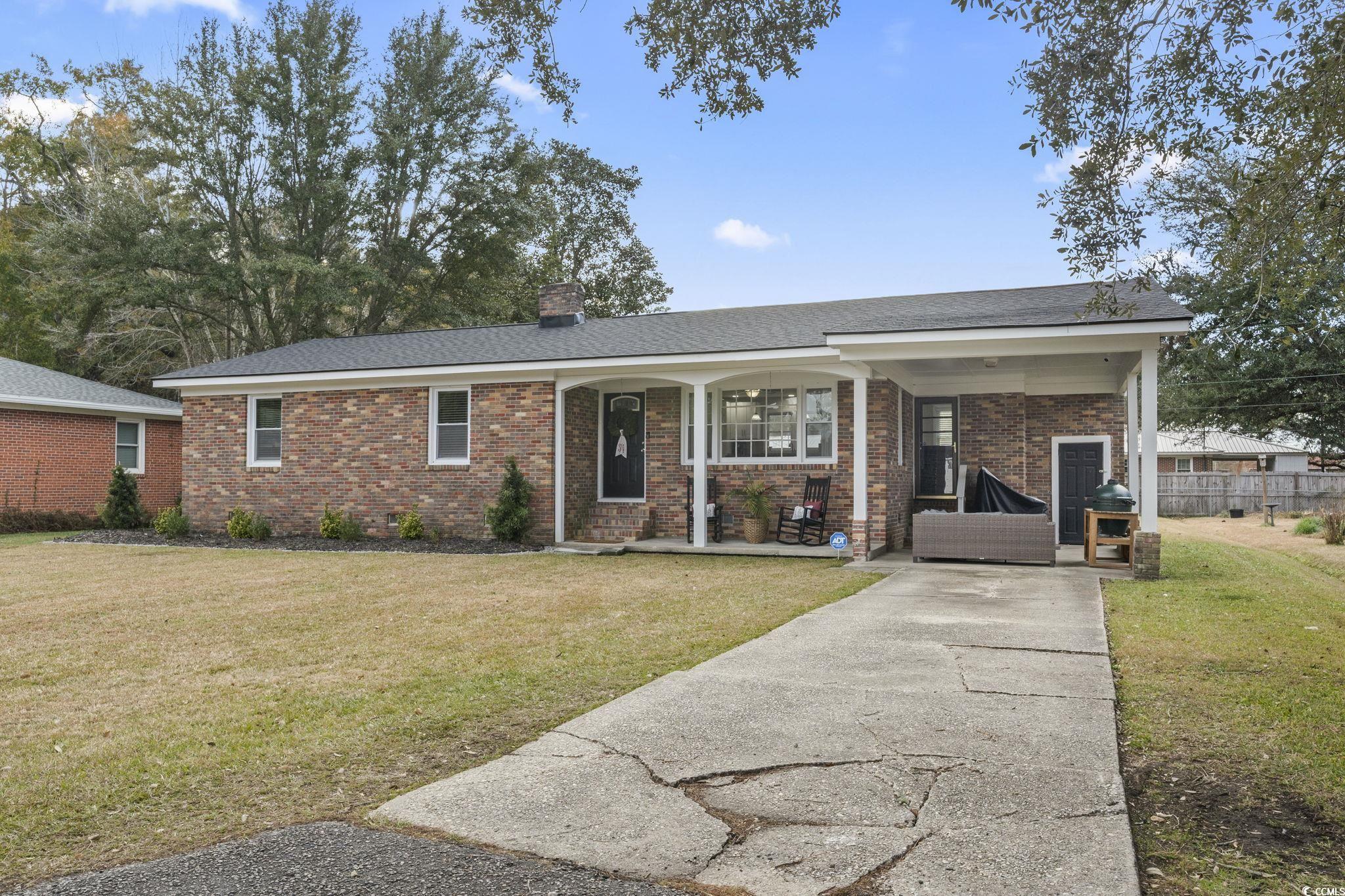 Ranch-style home with covered porch and a front ya