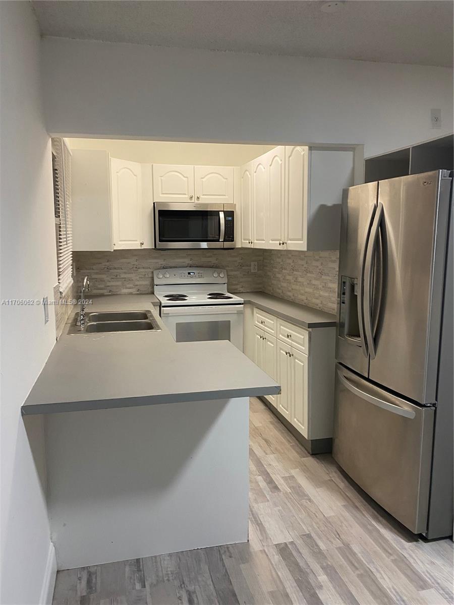 a kitchen with appliances a sink and a refrigerator