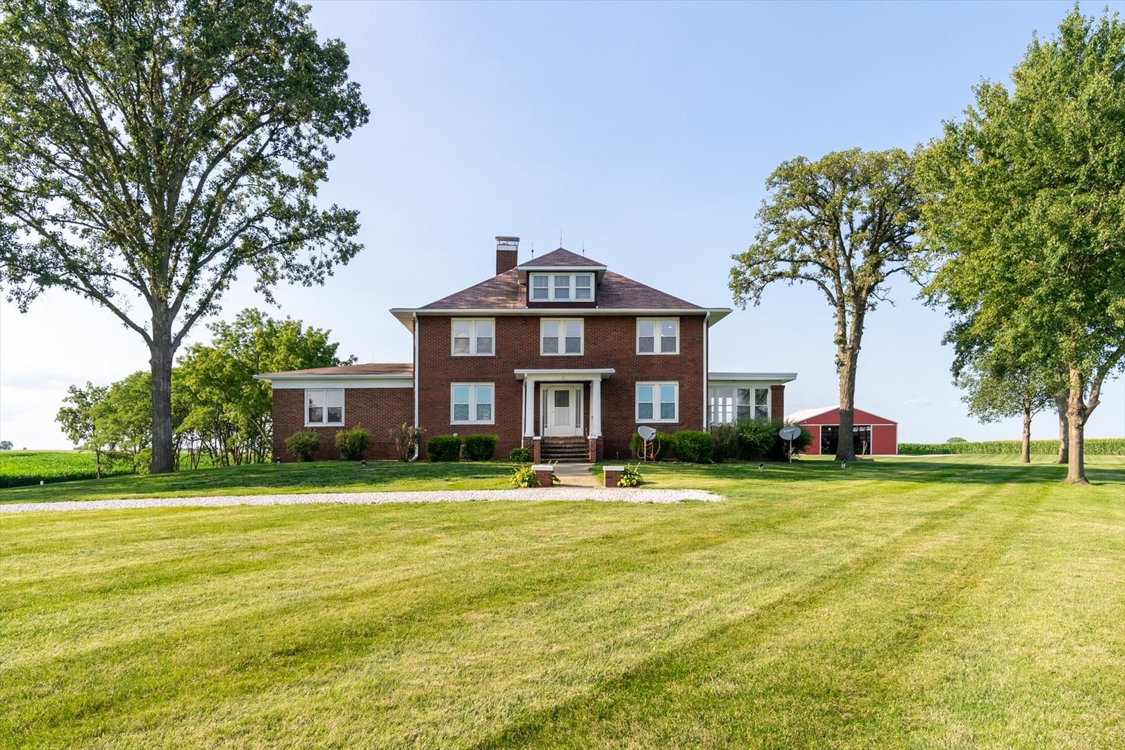 a view of a big house with a big yard and large trees