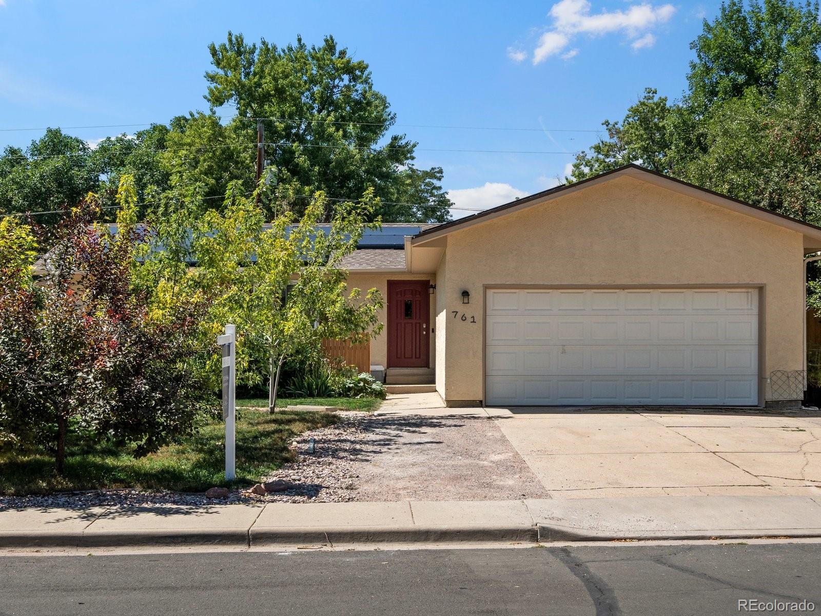 a front view of a house with garage and plants