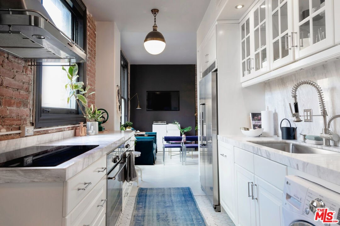 a kitchen with a sink dishwasher a stove and a dining table with wooden floor