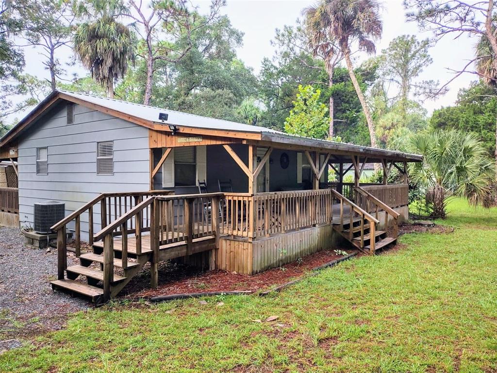 a view of a house with a yard and a wooden deck