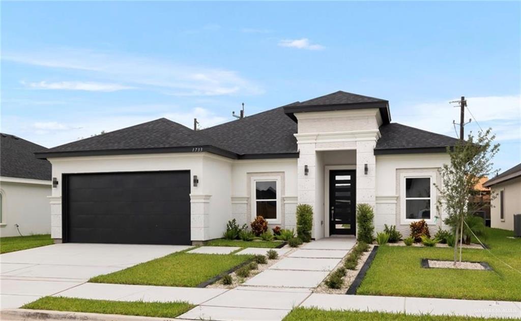 View of front of property with a garage and a front lawn