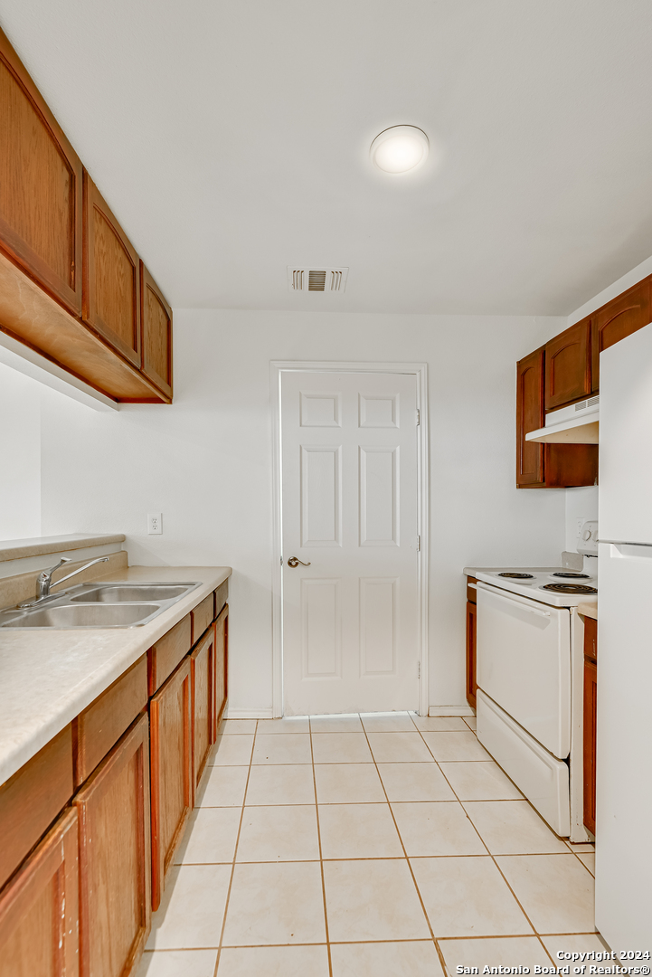 a kitchen with granite countertop a sink stove and cabinets