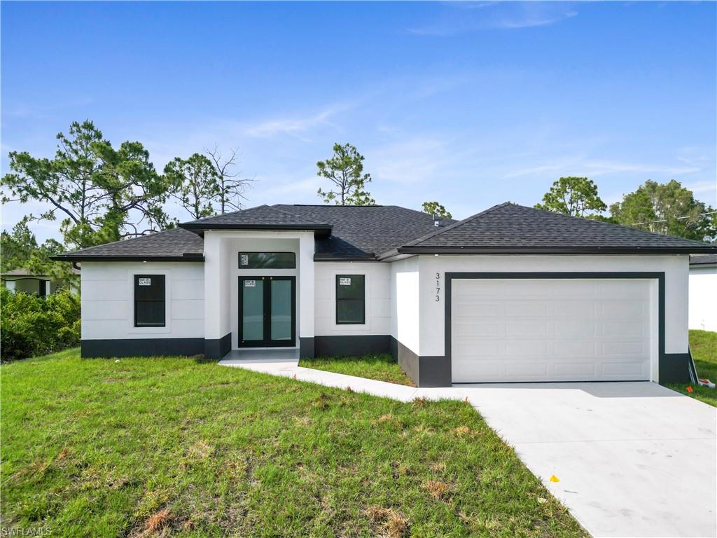 View of front of property featuring a front yard and a garage