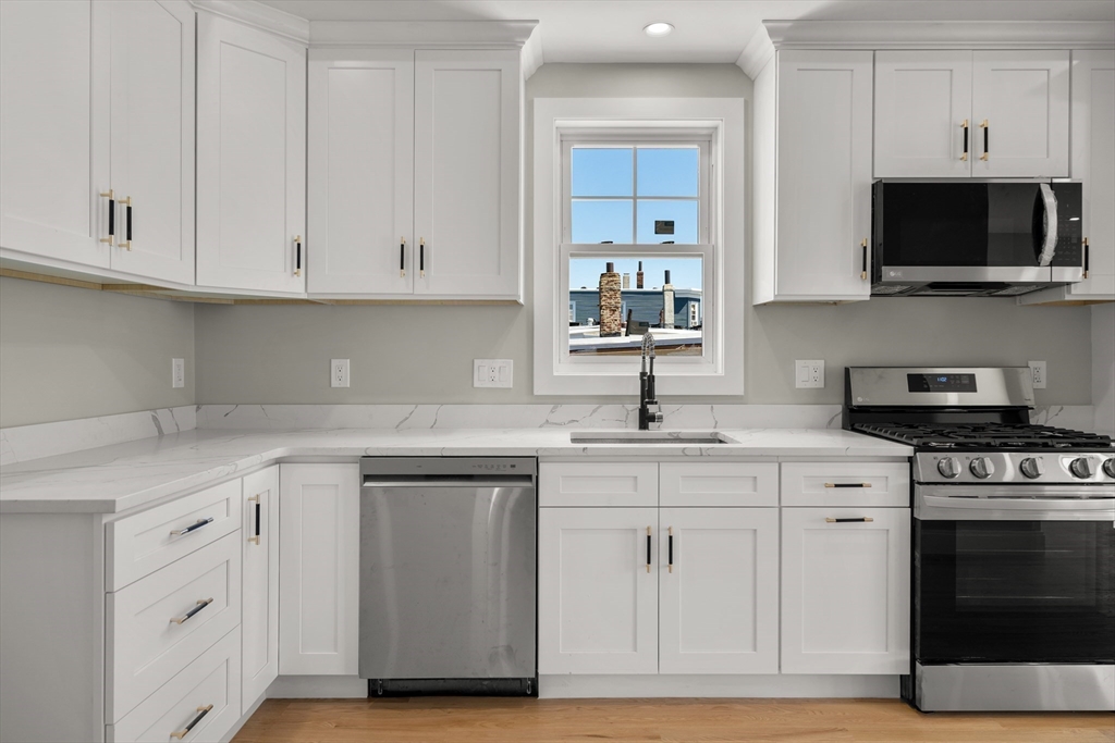 a kitchen with white cabinets and a stove with wooden floor