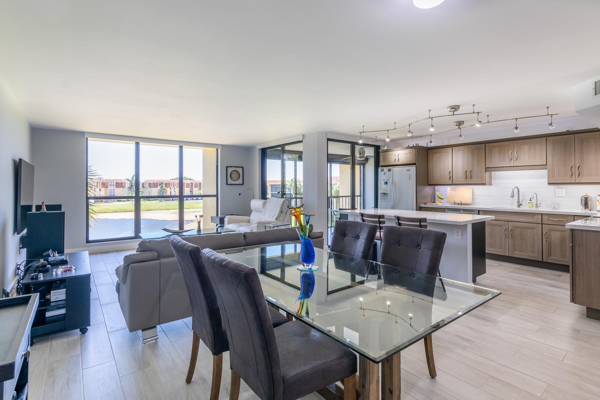 a living room with stainless steel appliances kitchen island granite countertop a table chairs and a dining table with wooden floor