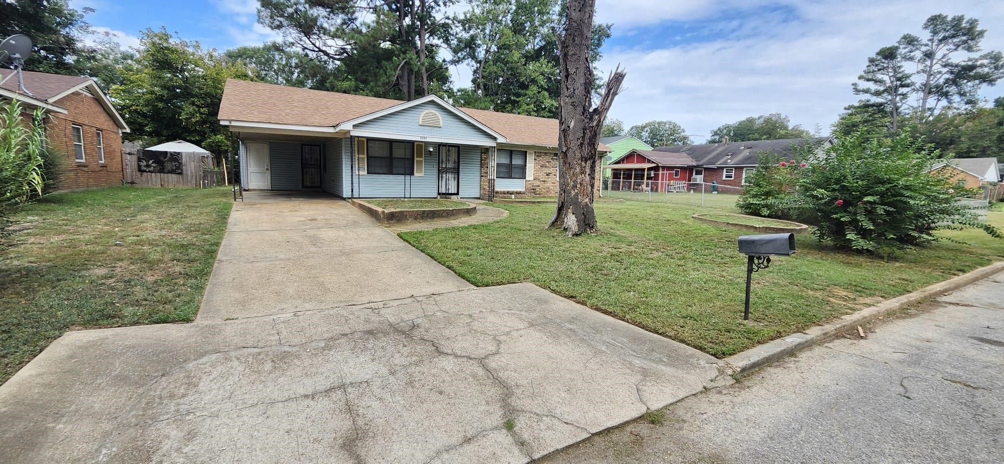 View of front facade featuring a front lawn, a porch, and a carport