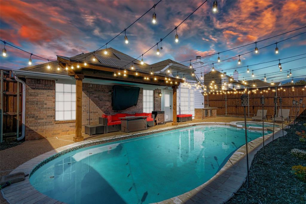 Pool at dusk featuring an in ground hot tub and a patio area