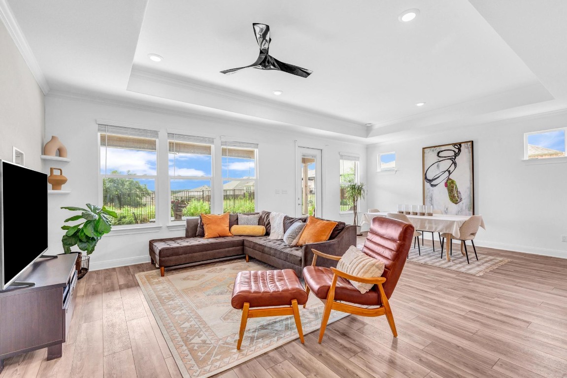 The moment you enter the living room, the blend of natural light from the large windows and the modern touches of recessed lighting and a contemporary fan creates an inviting atmosphere that feels both fresh and welcoming