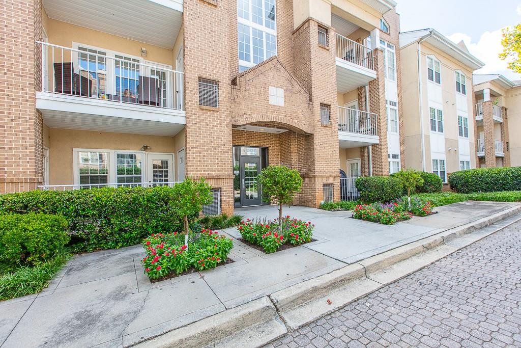 a front view of a multi story residential apartment building with yard and bench