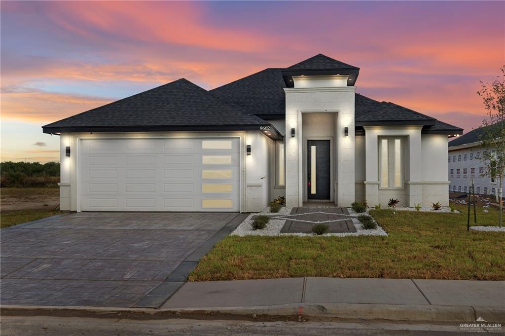 View of front facade featuring a garage and a lawn