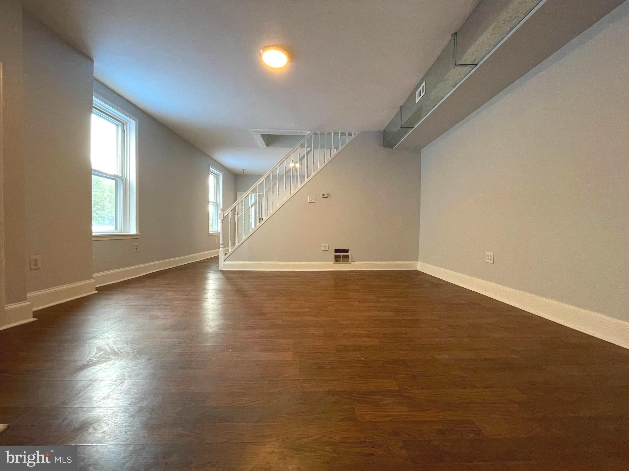 an empty room with wooden floor and windows