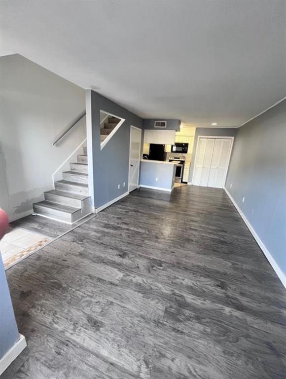 a view of an empty room with wooden floor and stairs