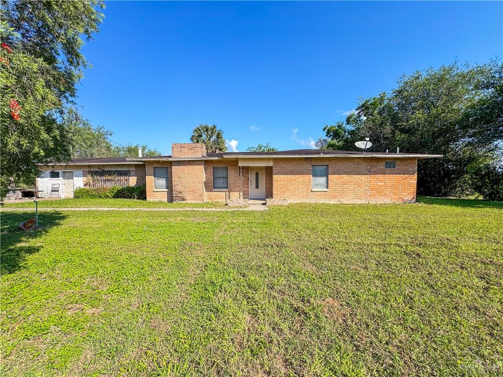 a front view of house with yard and trees in the background