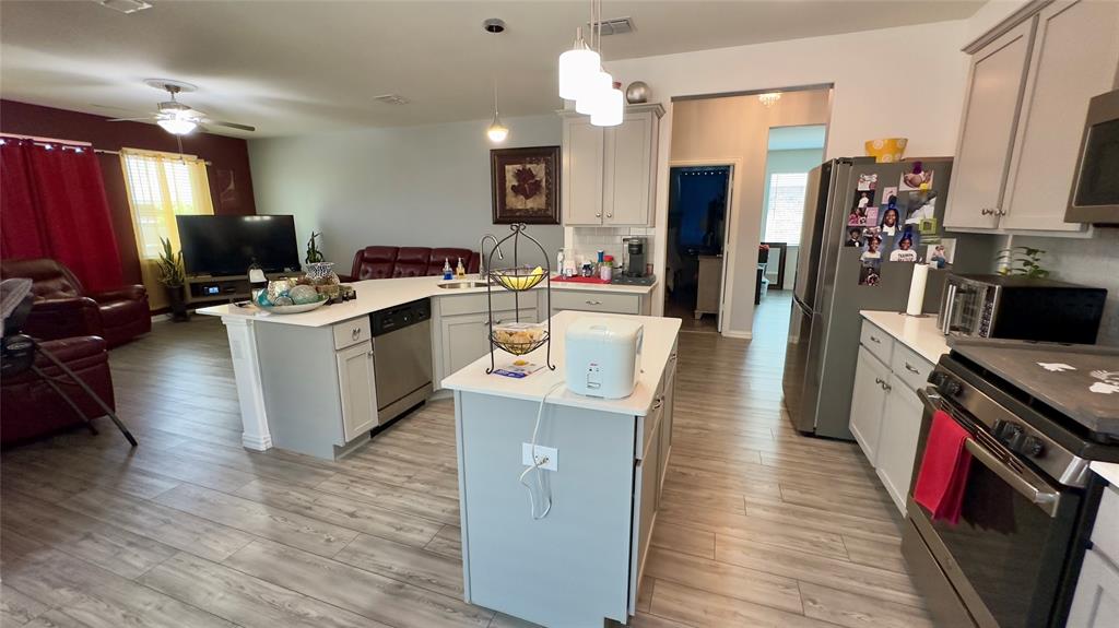 a living room with stainless steel appliances furniture a fireplace a flat screen tv and a view of kitchen