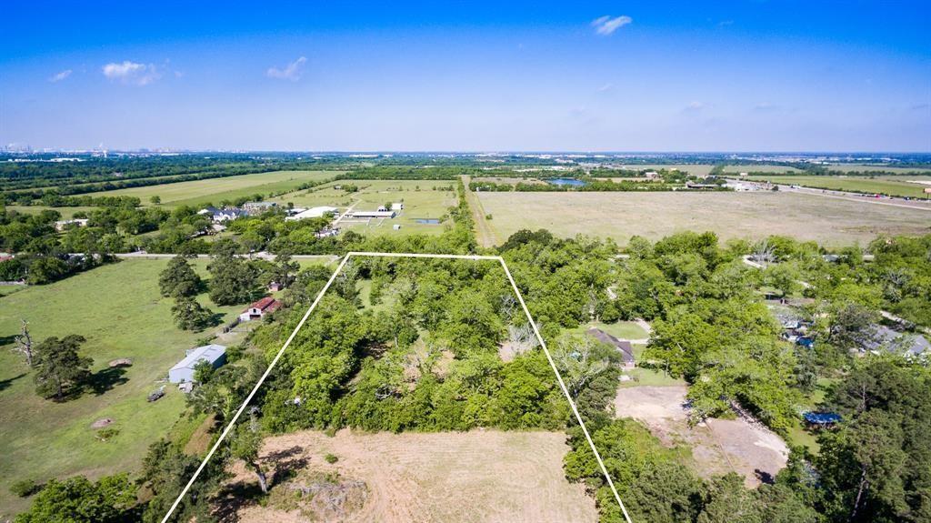 This aerial photo shows a spacious, undeveloped plot of land in a suburban area, surrounded by established homes with ample greenery and mature trees. The neighborhood appears peaceful and well-maintained, offering investor to develop the neighborhood along with convenience of nearby community infrastructure.