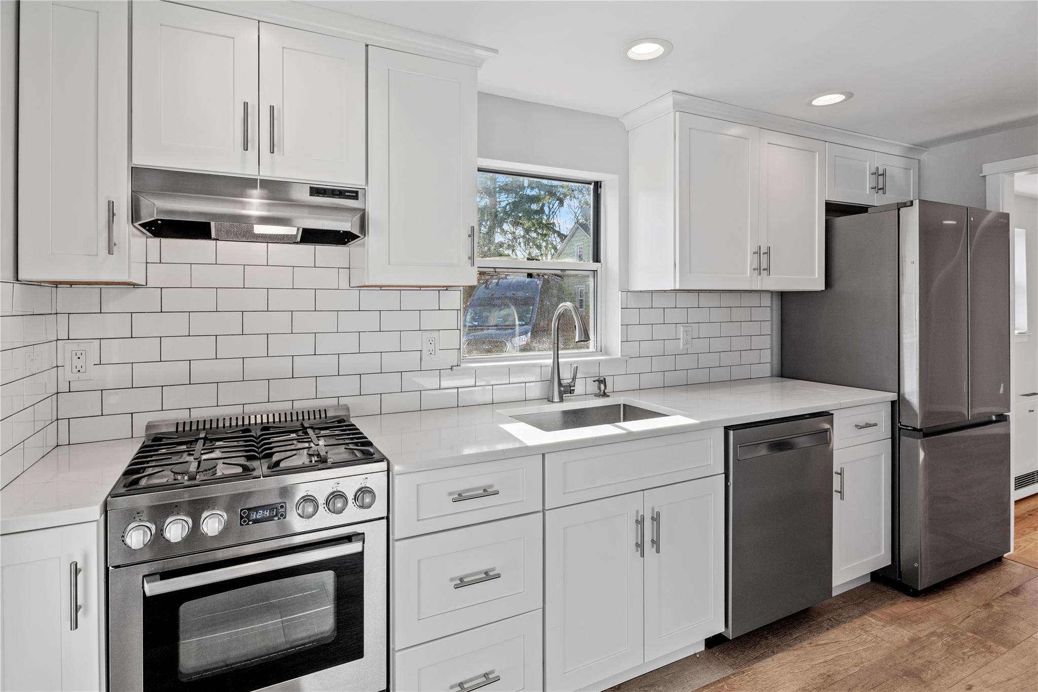 Kitchen featuring sink, stainless steel appliances, tasteful backsplash, light hardwood / wood-style floors, and white cabinets