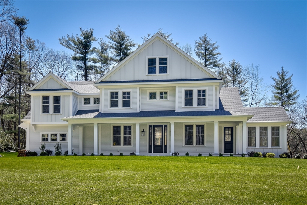 a view of a white house with a big yard and potted plants and large trees