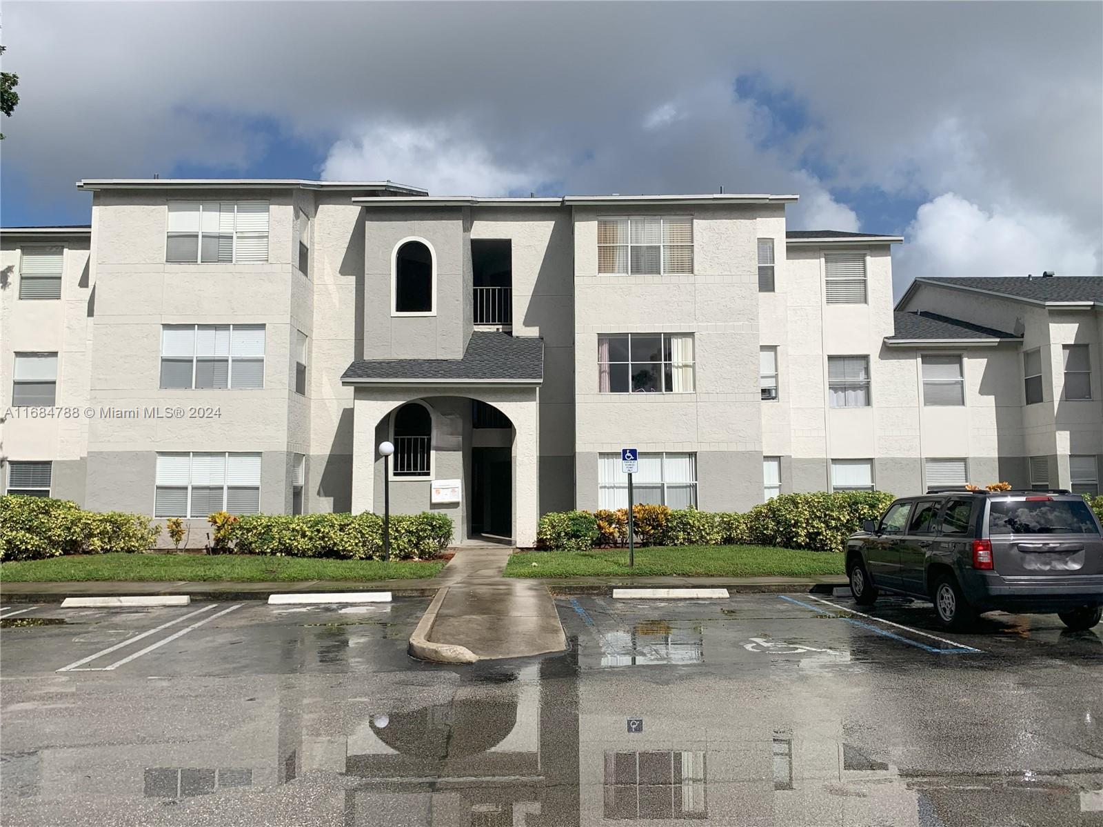 a front view of a building with cars parked