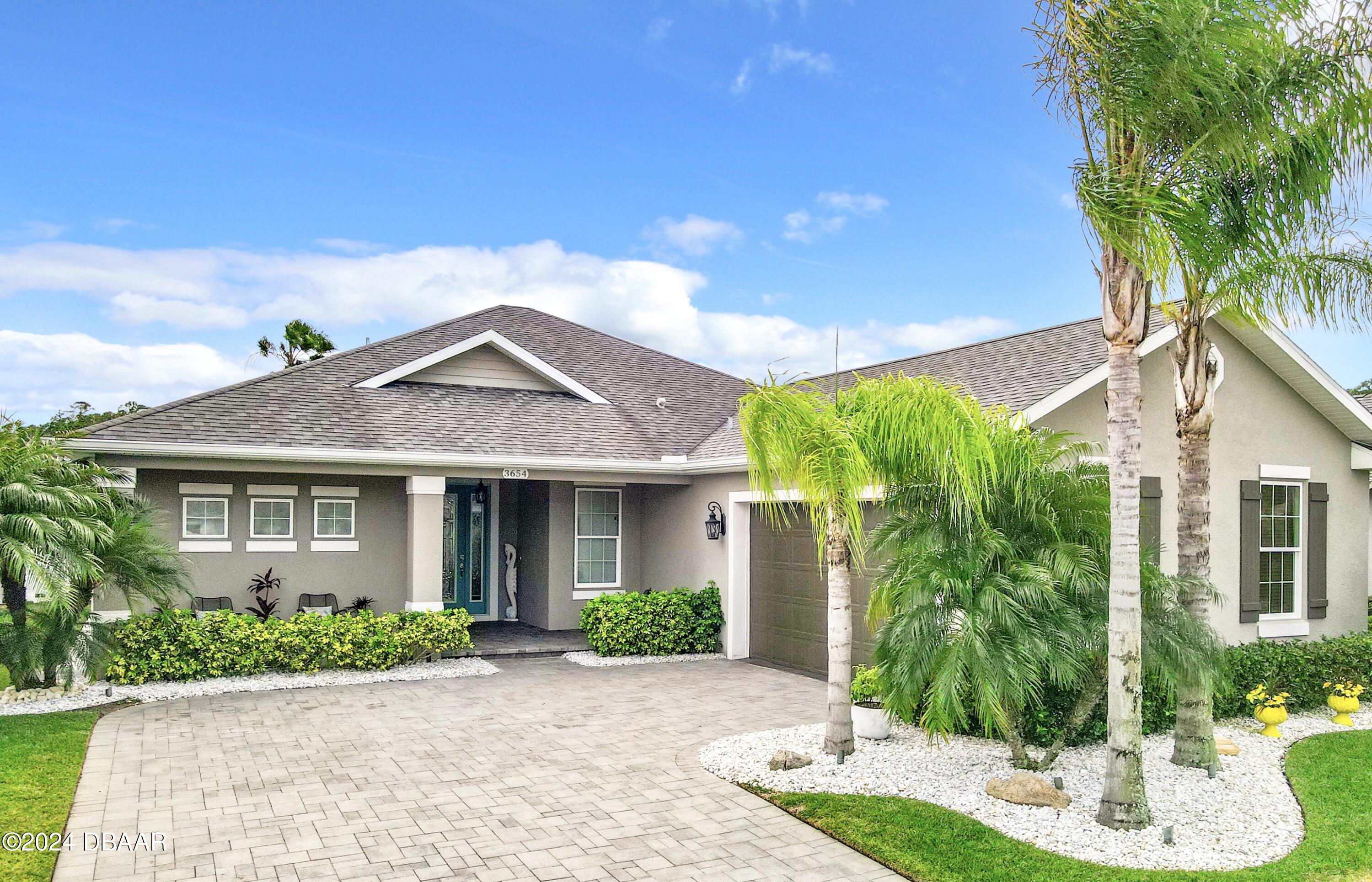 a front view of a house with a yard and potted plants