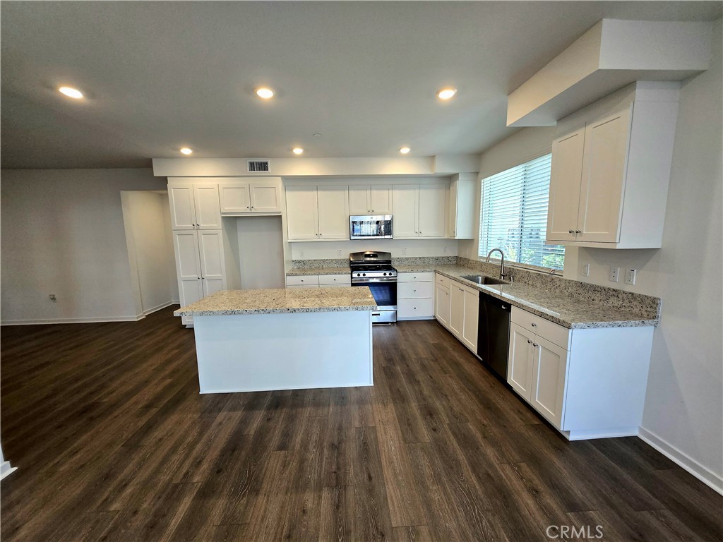 a large kitchen with stainless steel appliances granite countertop a stove a sink and a refrigerator