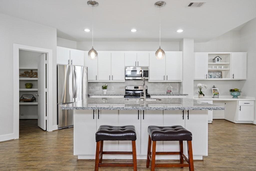 a kitchen with stainless steel appliances kitchen island granite countertop a table chairs sink and cabinets