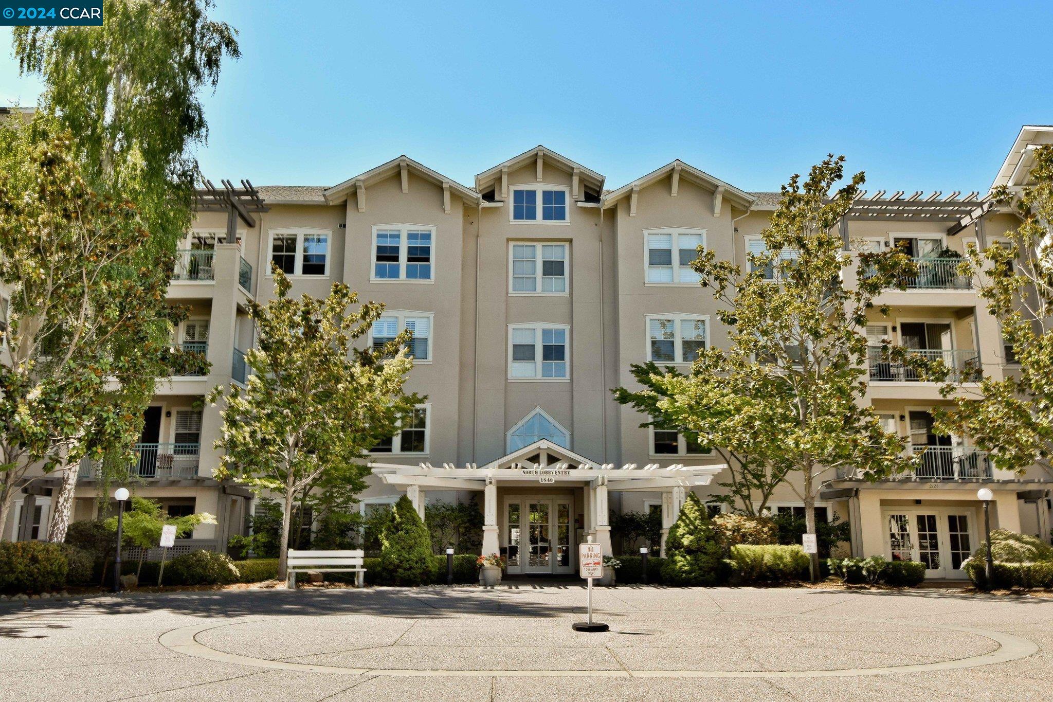 a front view of a residential apartment building with a yard and potted plants