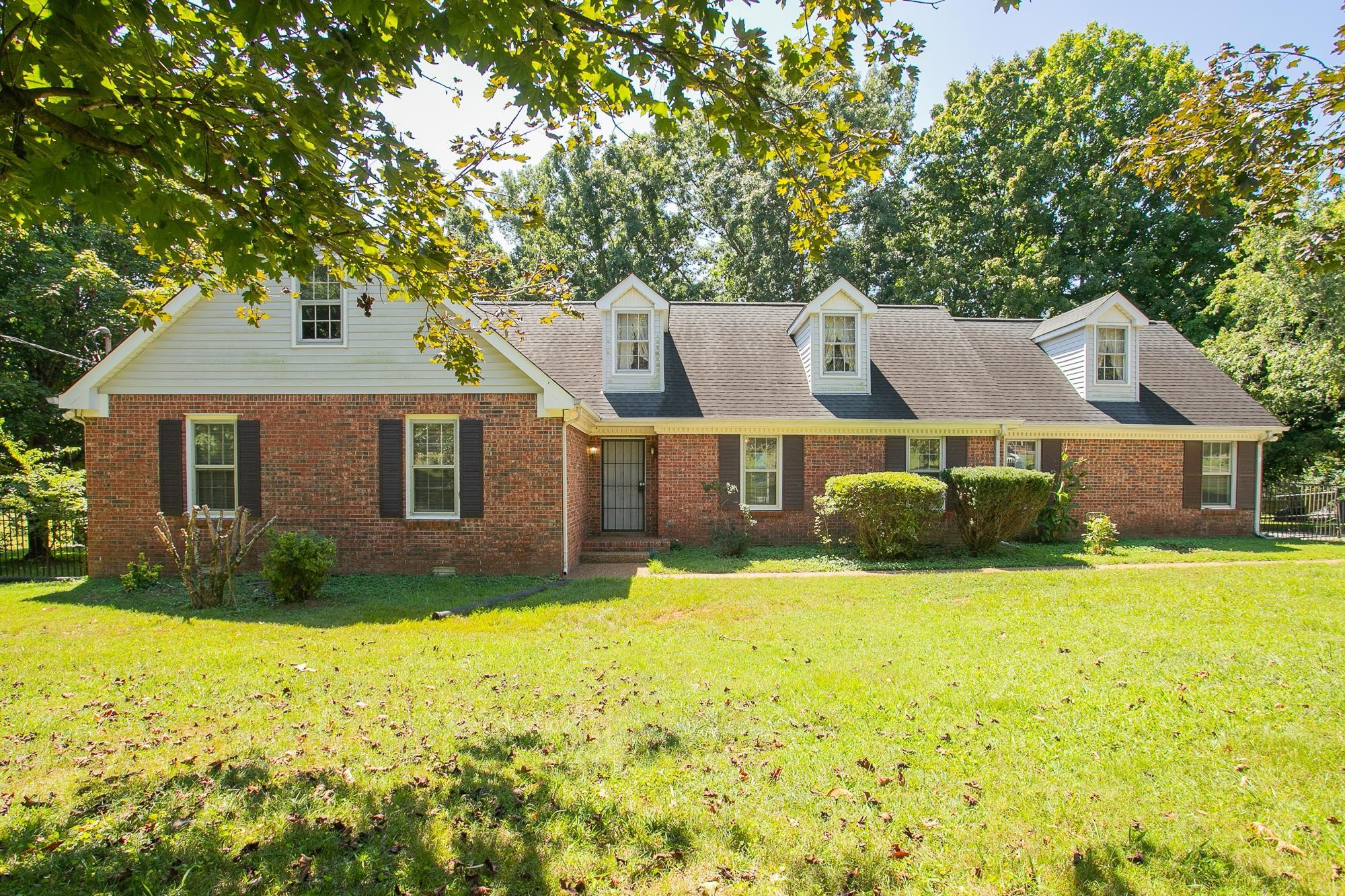 a view of a house with a yard and large trees