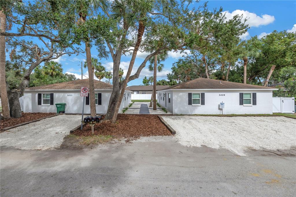 a view of a house with a yard and large tree